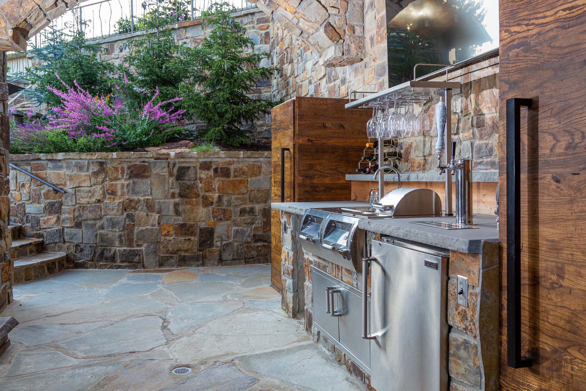 A built-in stainless grill set into a stone outdoor kitchen