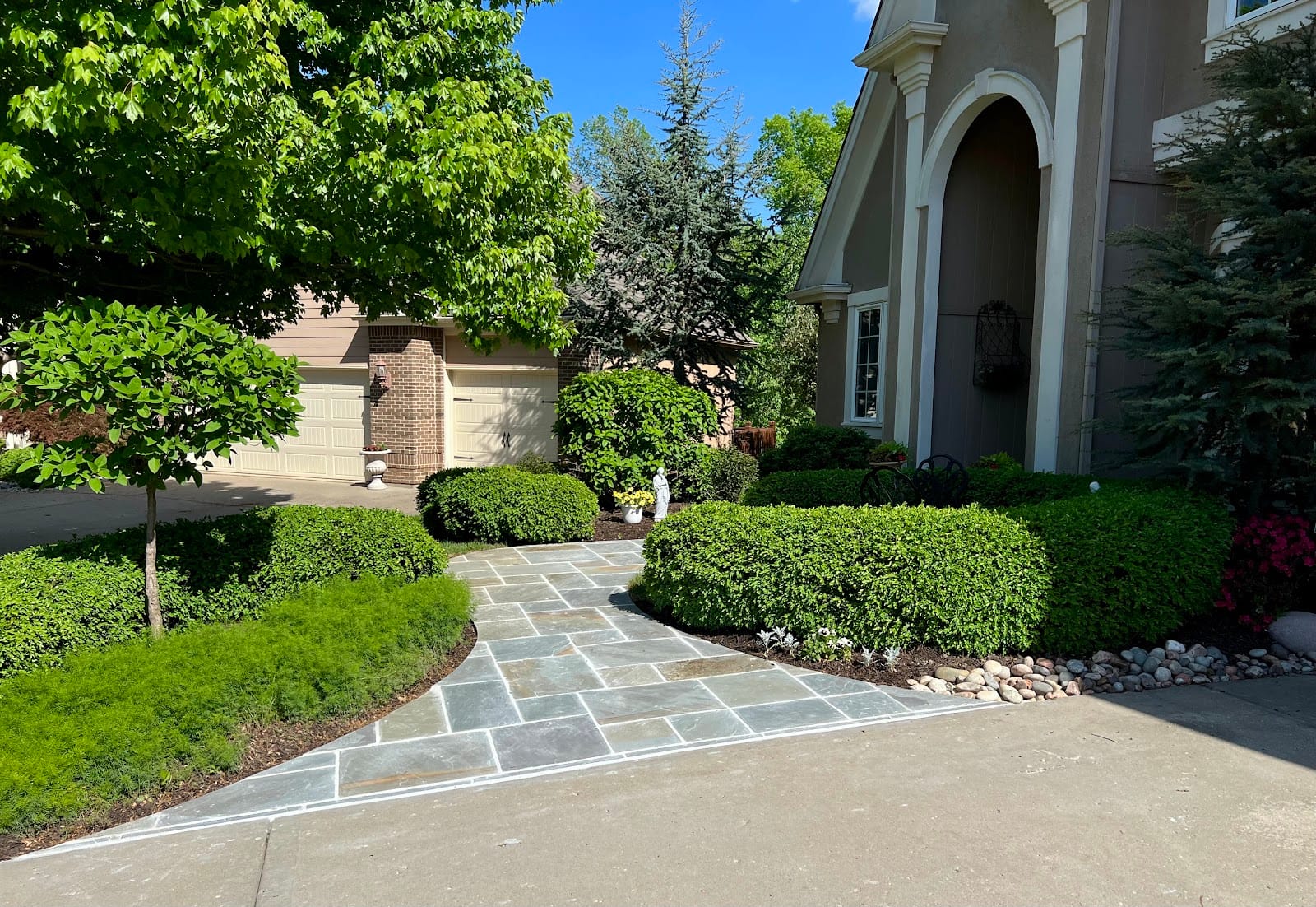 A well-kept upscale home with a flagstone drive and manicured plantings