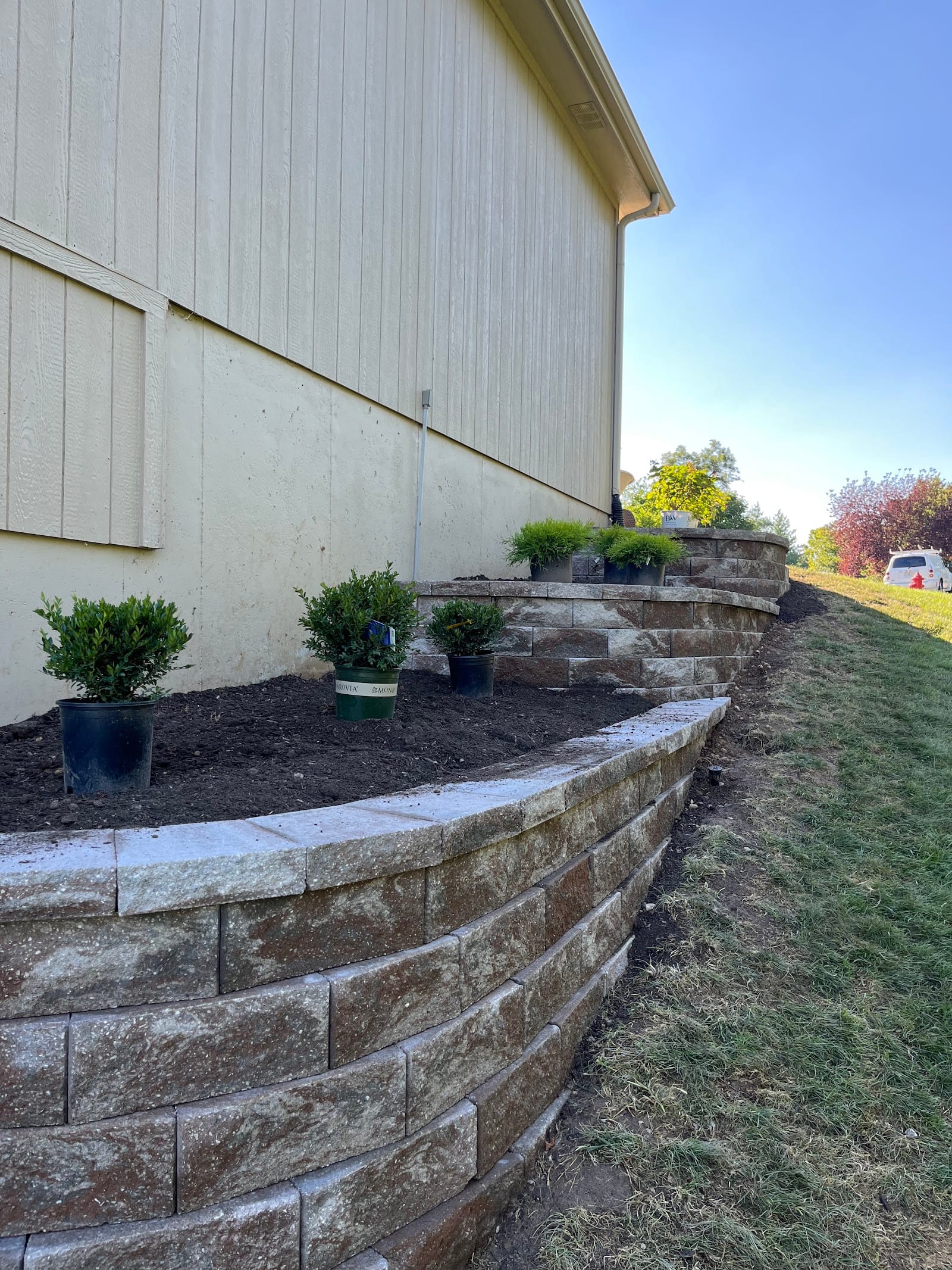 A tiered block retaining wall holding a planted slope