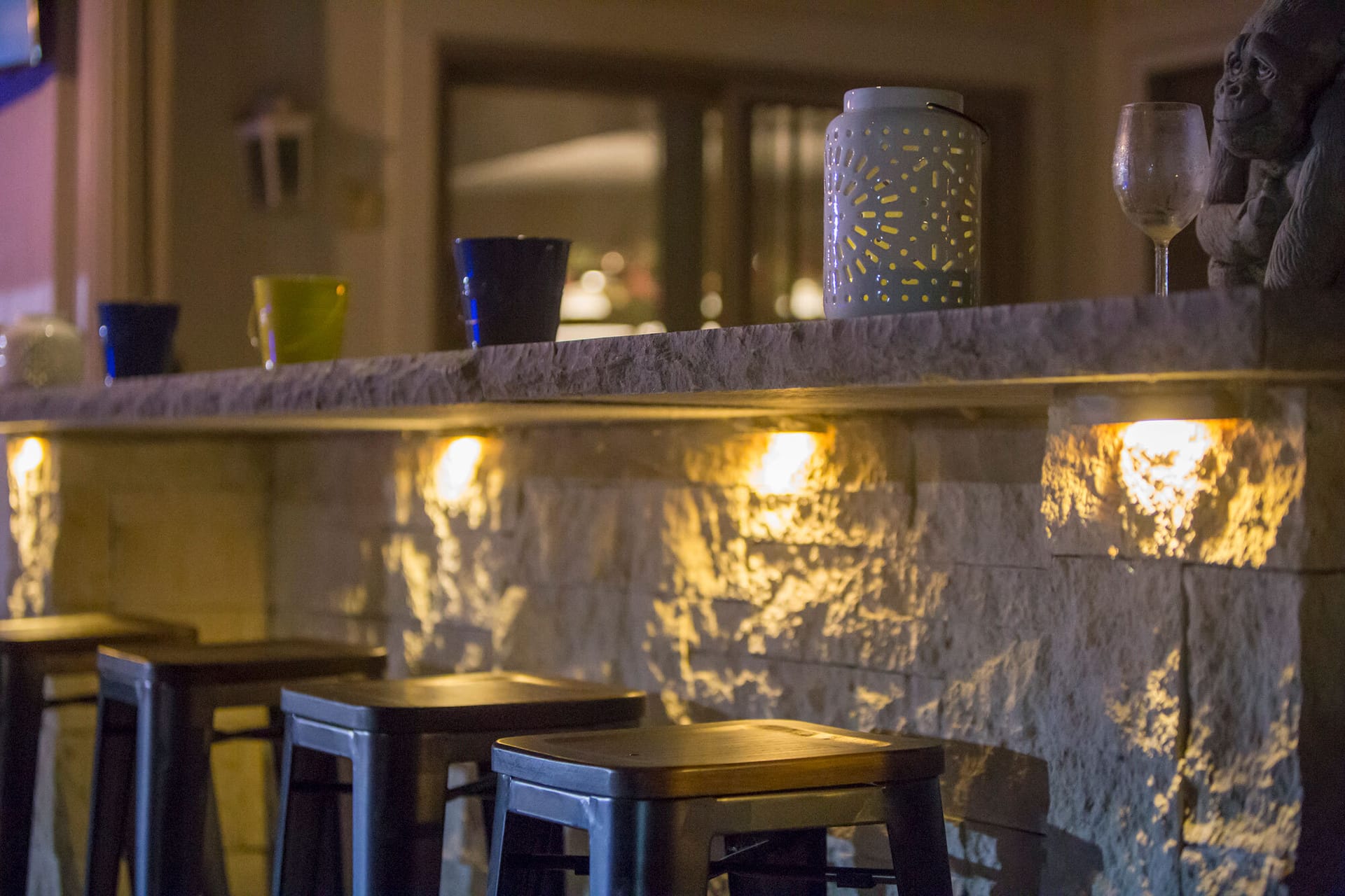An outdoor bar counter lit at night with By The Blade LED landscape lighting in Leawood